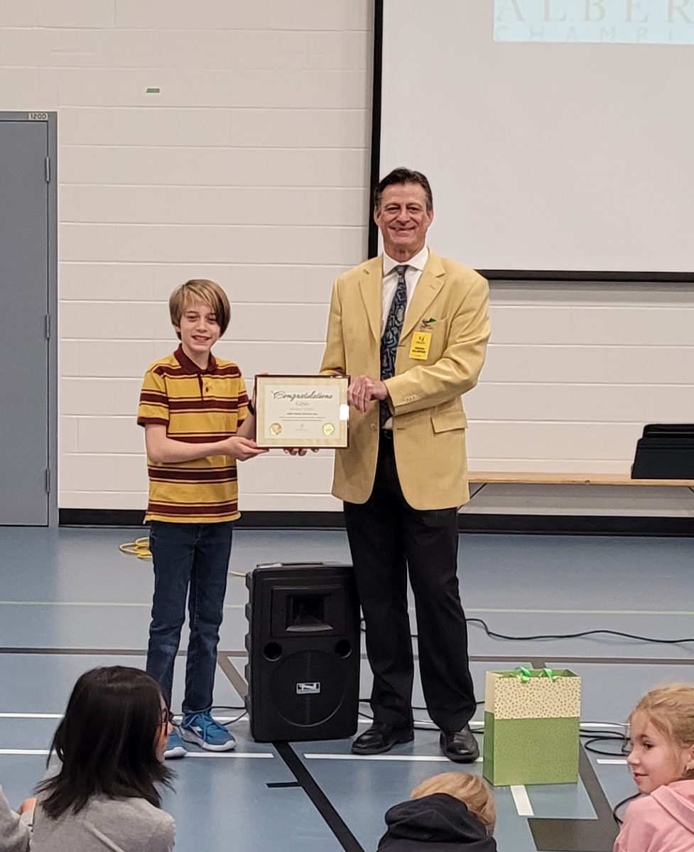 Matthew Tinsley accepting 1st Place Award (4-6) at St Cecilia School from Mark Ruthenberg of Alberta Champions